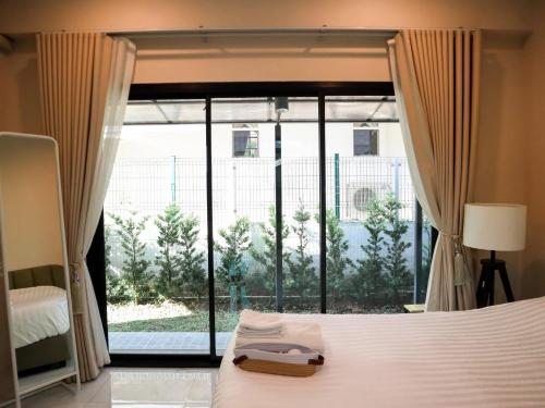 a bedroom with a bed and a large window at Khunnapat Pool Villa Khaoyai in Mu Si
