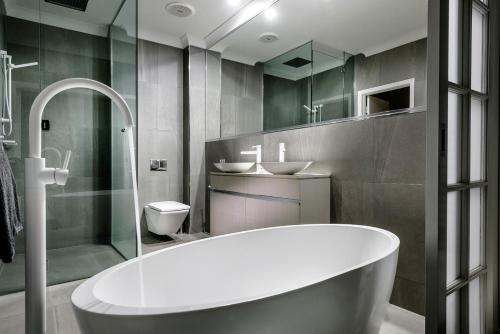 a bathroom with a tub and a sink and a toilet at Mangrove Hotel in Broome