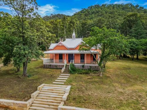 an orange house in a field with trees at Glenrock Homestead in Bulga
