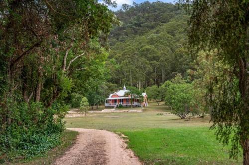 a dirt road leading to a house in the forest at Glenrock Homestead in Bulga