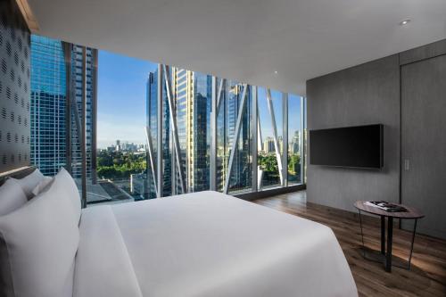 a bedroom with a large white bed and a large window at Discovery SCBD Jakarta in Jakarta