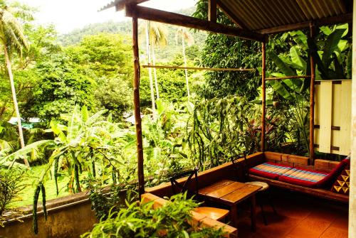 a porch with a bench and a view of the forest at Rock Inn Bailan in Ko Chang