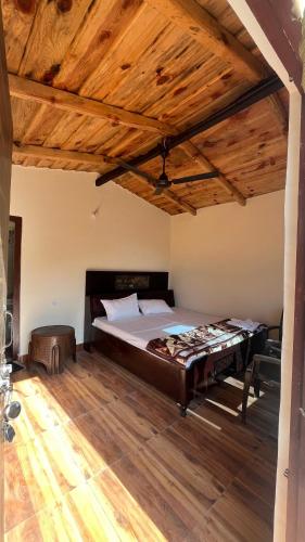 a large bed in a room with a wooden ceiling at Luvyash Campsite Stays in Bhīm Tāl