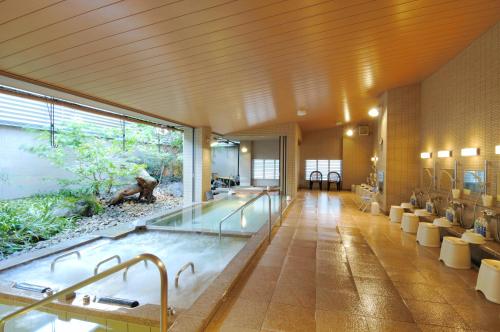 Kanazawa Manten Hotel Ekimae في كانازاوا: حمام كبير مع حوض استحمام ساخن في الوسط