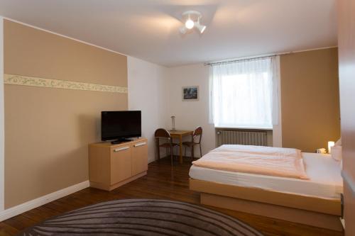 um pequeno quarto com uma cama e uma televisão em Apartment Haus em Kleinblittersdorf