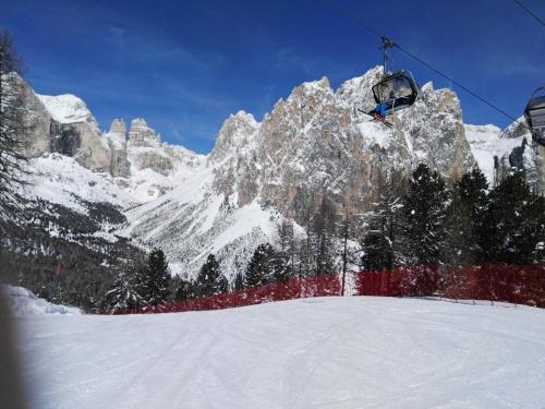 a person riding a ski lift over a snow covered mountain at Ciasa Savoy in Vigo di Fassa