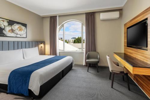 a hotel room with a bed and a desk and a television at BEST WESTERN PLUS Travel Inn in Melbourne