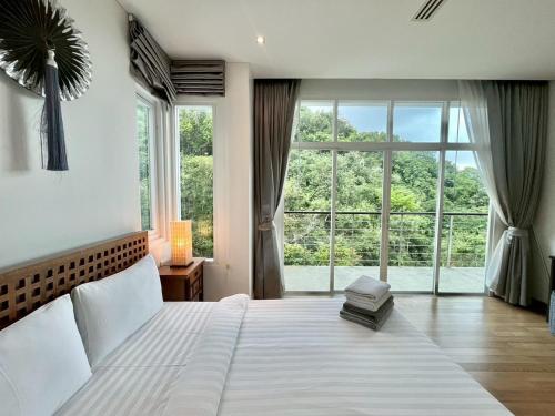 a bedroom with a large bed with a large window at Grand Kamala Falls in Kamala Beach