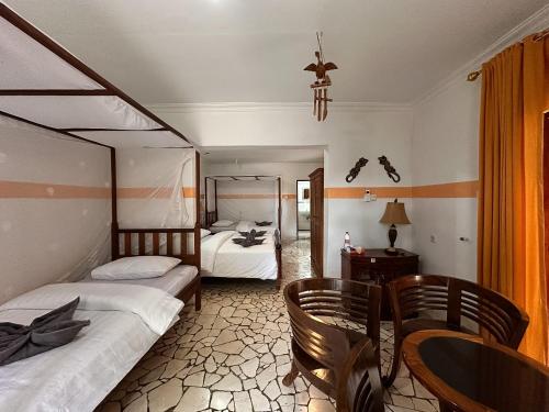 a bedroom with two beds and a table and chairs at Mangga Lodge in Bira