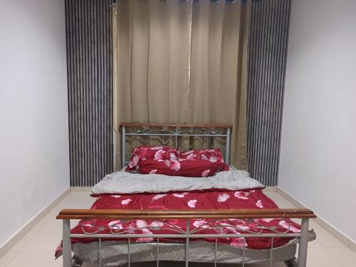 a bed with red sheets and pillows in a room at Aisyhome in Jitra