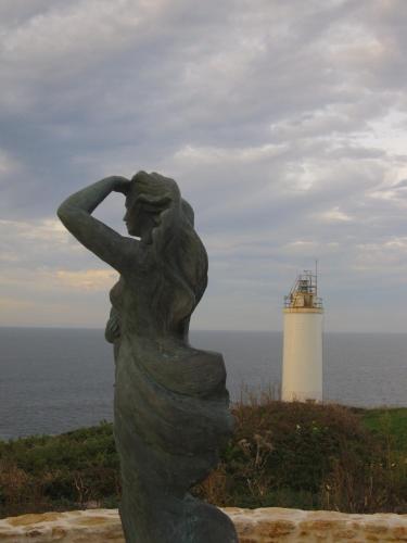 a statue of a woman with a lighthouse in the background at Hotel Playa de Laxe in Laxe