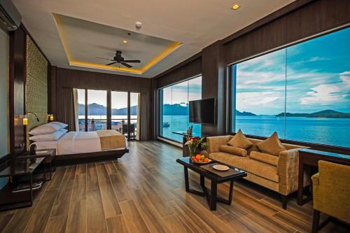 een slaapkamer met een bed en een bank en een groot raam bij Two Seasons Coron Bayside Hotel in Coron