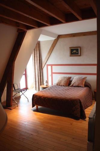 une chambre avec un grand lit dans un grenier dans l'établissement Le Haut-Val Résidences, à Bellême