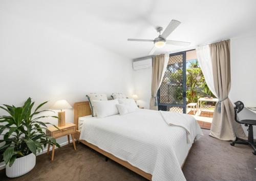 a white bedroom with a bed and a window at Salad Days -Beachfront & Pet Friendly in Marcoola
