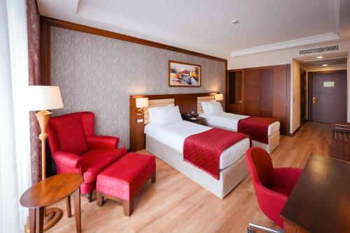 a hotel room with two beds and red chairs at Wellborn Luxury Hotel in Kocaeli