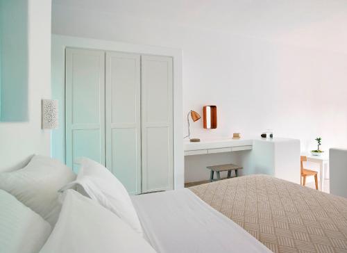 a white bedroom with a bed and a desk at Unique Milos Suites in Pollonia