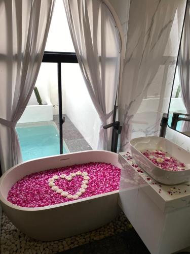 a bath tub filled with pink flowers in a bathroom at Numar Villas Yogyakarta in Seturan