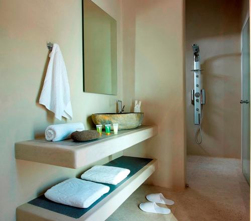 a bathroom with a sink and a shower with towels at Unique Milos Suites in Pollonia