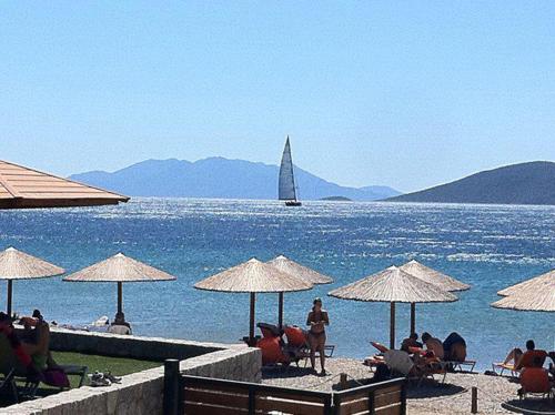 a group of people sitting on a beach with umbrellas at Belvedere Suites Korfos in Korfos