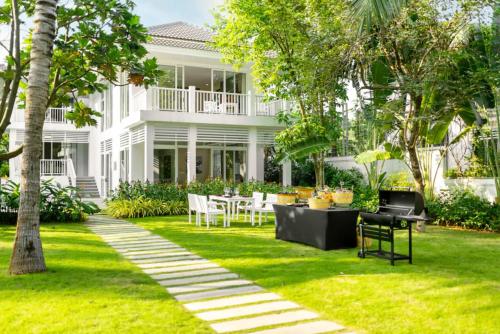 a white house with a table and chairs in the yard at Luxury Private Pool Villas at Village Danang Resort in Danang