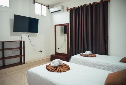 two beds in a room with a mirror and a tv at Carpao Lodging Galapagos in Puerto Ayora