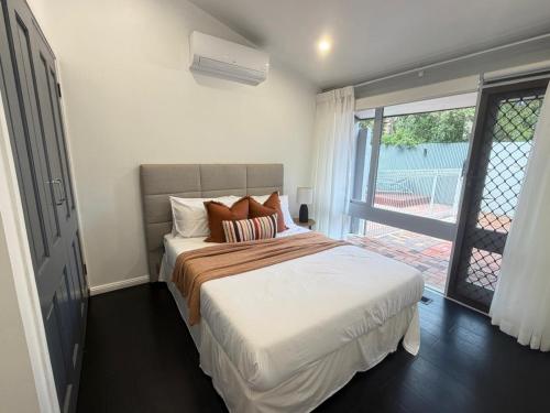 a bedroom with a bed and a large window at Tranquil bush resort house - pool & fire pit in Pymble