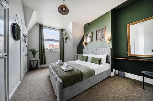 a bedroom with a large bed with green walls at Clarence House in Llandudno