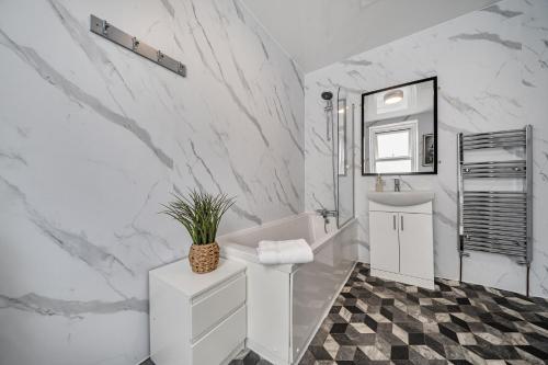 a white bathroom with a white tub and a sink at Clarence House in Llandudno