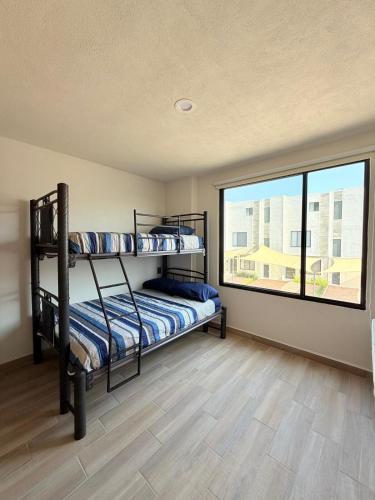 a bedroom with bunk beds and a large window at Xochitepec Residencial in Atlacholoaya