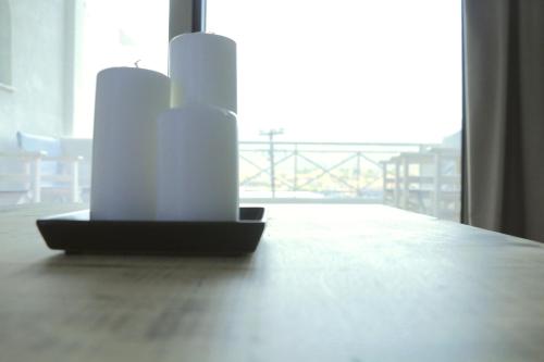two white candles sitting on a table near a window at Belvedere Suites Korfos in Korfos