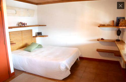 オルタにあるCasa do Porto da Hortaの白いベッドと壁に棚が備わるベッドルーム1室