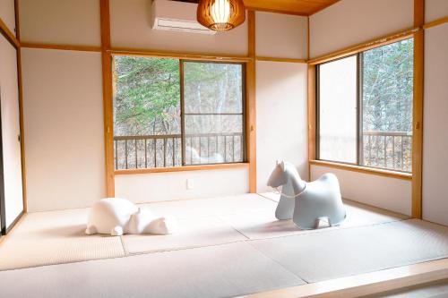 two stuffed animals sitting on a bed in a room with windows at rinne 北軽井沢 Forest2 in Tsumagoi