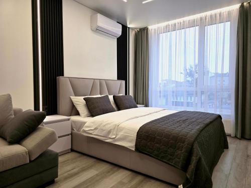 a bedroom with a bed and a couch and a window at Belvedere Apart, parking in Ivano-Frankivsk
