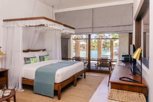 a bedroom with a bed and a desk and a television at Kayaam Wellness in Tangalle