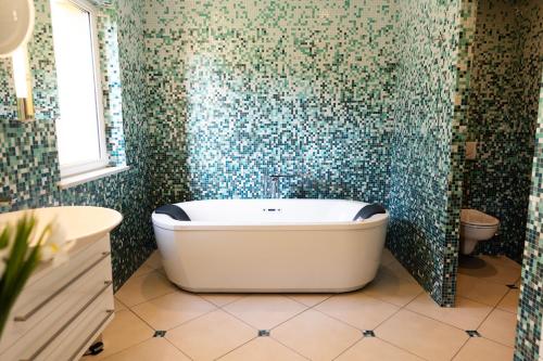a bath tub in a bathroom with green mosaic tiles at Domaine de Thironne Lac & Nature in Montigny-le-Chartif