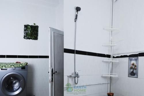 a bathroom with a washing machine and a shower at earth home in Imzoûrene