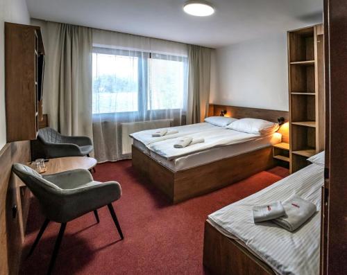 a hotel room with two beds and a chair at Penzion Horalka in Hlinsko