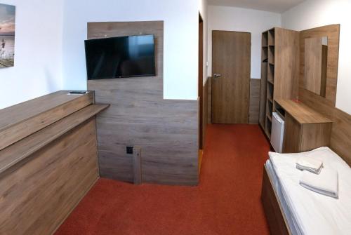 a room with a bed and a tv on a wall at Penzion Horalka in Hlinsko