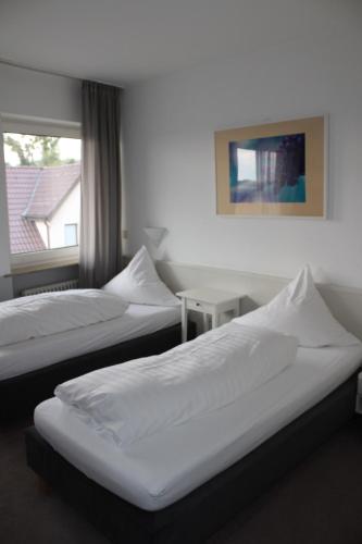 two beds in a hotel room with a window at RB Hotel Linde in Wangen