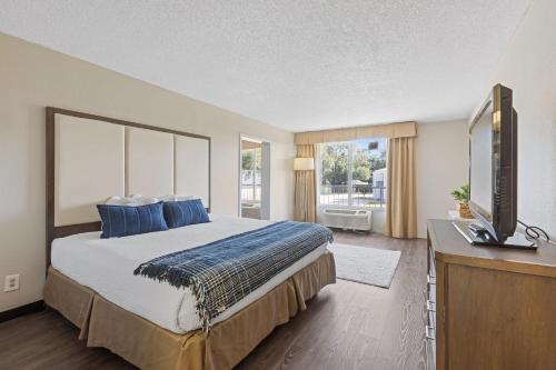 a bedroom with a bed with blue pillows and a television at Ramada by Wyndham Houma in Houma
