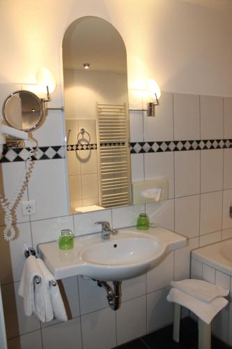 a bathroom with a sink and a mirror and a tub at RB Hotel Linde in Wangen