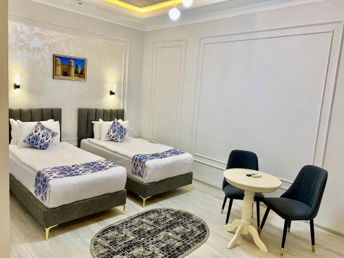 a bedroom with two beds and a table and chairs at Isakhoja Boutique Hotel in Khiva