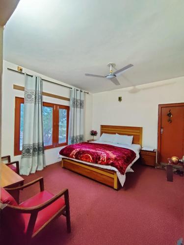 a bedroom with a bed and a chair in it at Indus Motel in Skardu