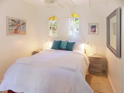 ein weißes Bett in einem Zimmer mit 2 Fenstern in der Unterkunft Aratinga Inn in Abraão