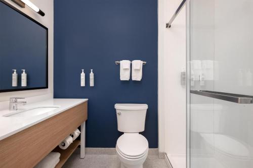 a blue bathroom with a toilet and a glass shower at Spark by Hilton Douglasville Atlanta West in Douglasville