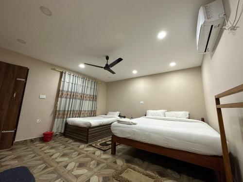 a bedroom with two beds and a ceiling fan at Narayani View Resort in Bharatpur