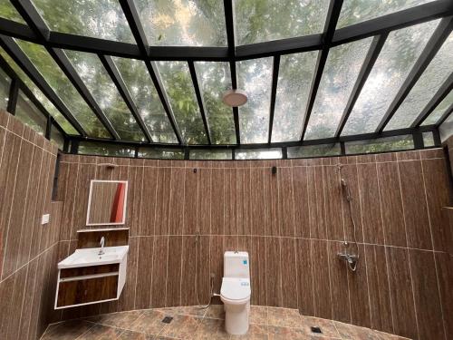a bathroom with a toilet and a glass ceiling at Infinity Farm Grove in Olavakod Junction