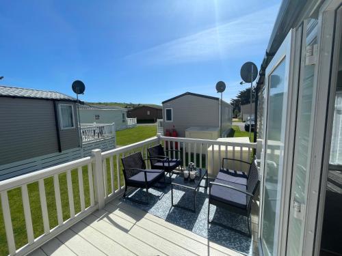 a deck with chairs and tables on a house at Golden Dunes Retreat, Dog-Friendly Stay at Par Sands Holiday Park, Cornwall in Par