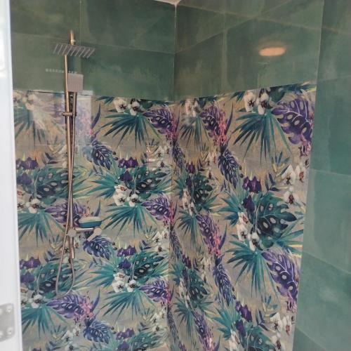 a bathroom with a shower with a tropical wallpaper at Blu Corner in Lian