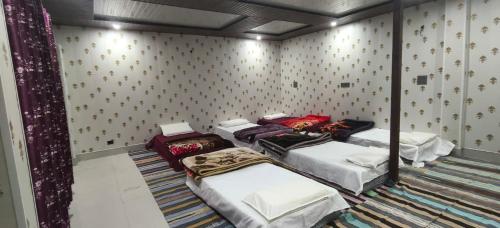 a room with four beds in a room with wallpaper at Omji Niwas - Kalindi in Kharsālī